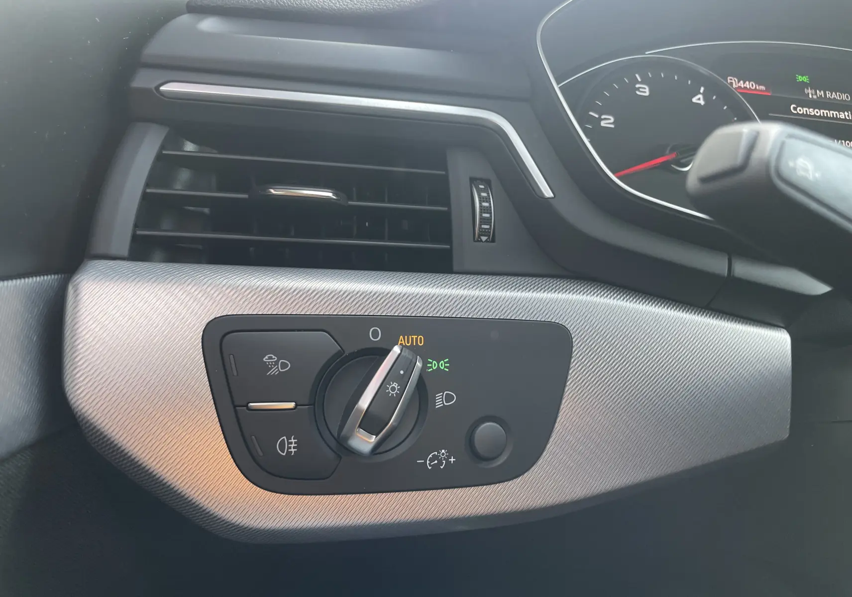 Détail du tableau de bord côté gauche de l'Audi A4 Avant 40 TDI blanc, avec commande d'éclairage en position auto.