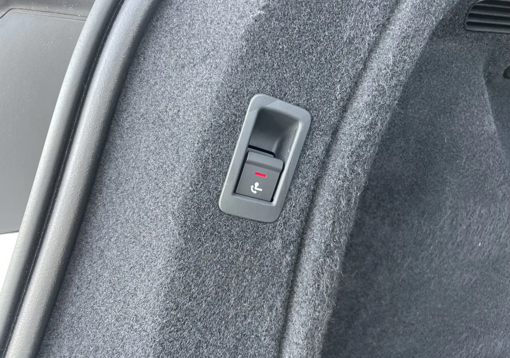 Bouton de déverrouillage du siège arrière dans le coffre d'une Audi A4 Avant blanc 40 TDI 204 Quattro 2022.