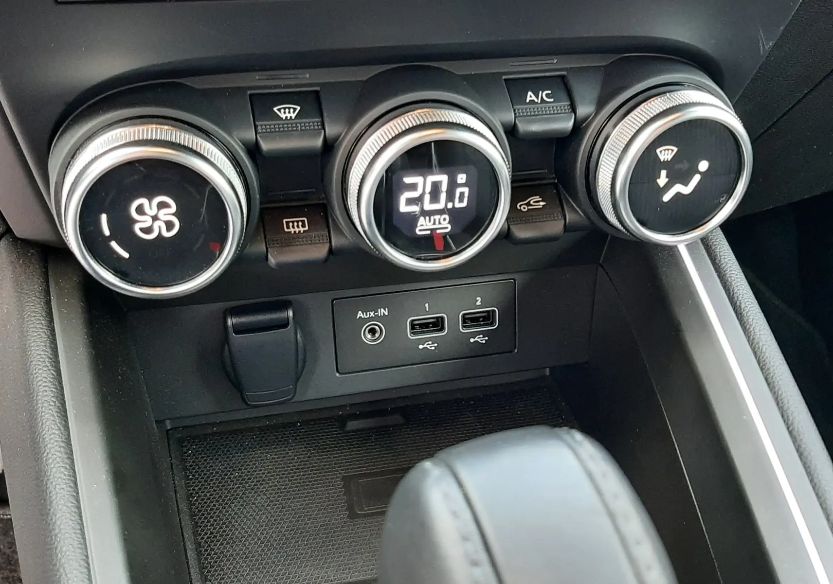 Gros plan sur la console centrale de la Renault Clio V gris titanium, montrant les commandes de climatisation et ports USB.