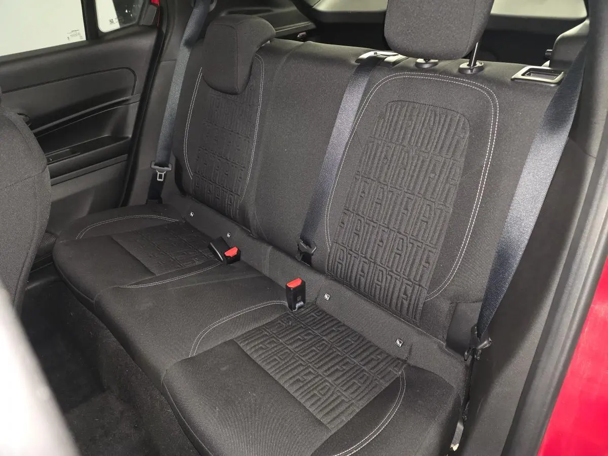 Banquette arrière en tissu noir avec monogramme FIAT, vue côté droit de l'habitacle rouge du FIAT 600 Hybrid 2024.