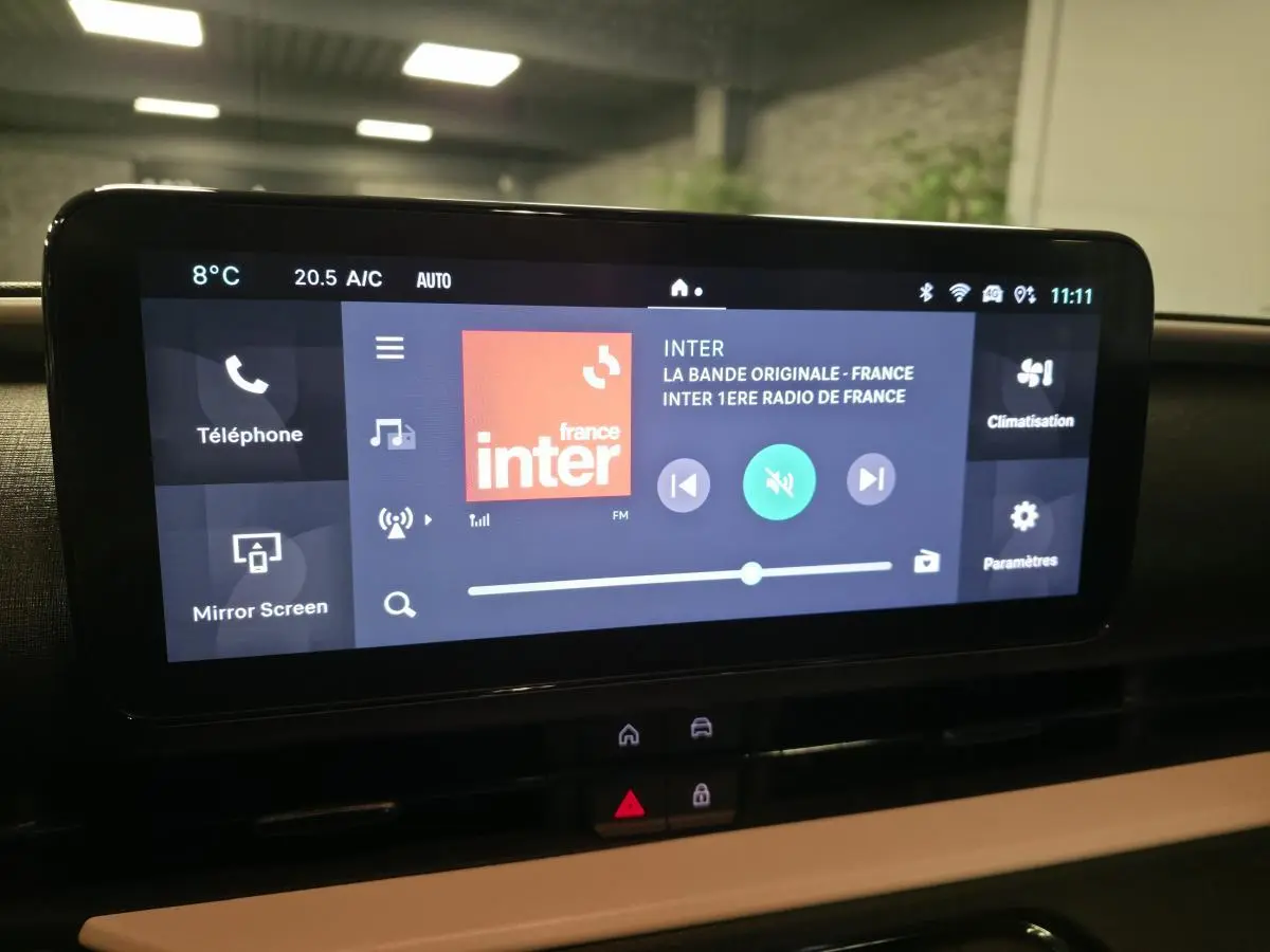 Écran tactile central du tableau de bord de la FIAT 600 rouge, affichant la radio France Inter en intérieur.