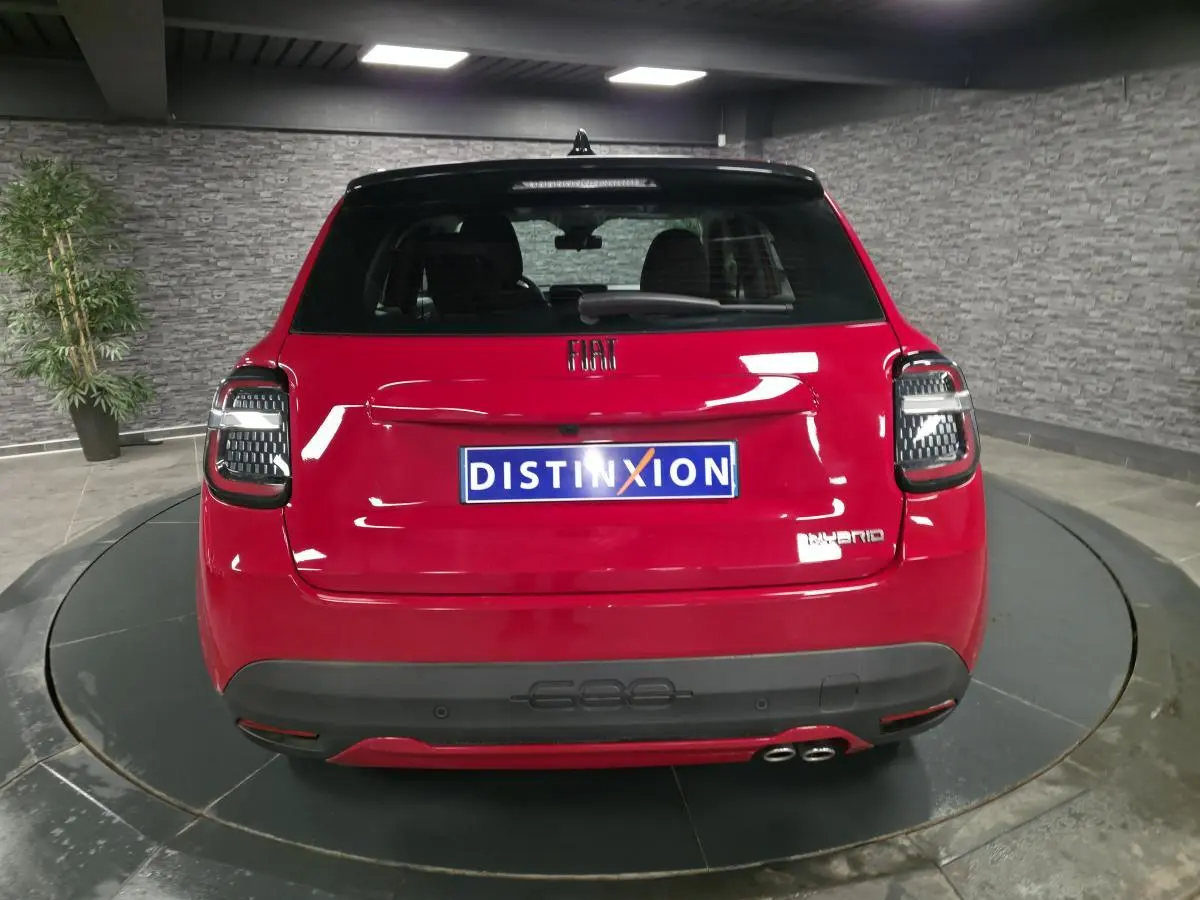 Vue arrière d'une FIAT 600 hybride rouge 2024 avec double sortie d'échappement côté droit et feux arrière LED noirs.