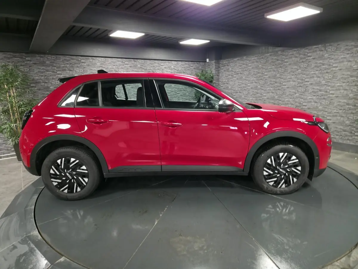 Vue de profil côté gauche d'une FIAT 600 rouge 2024 avec jantes noires et coques de rétroviseurs argentées.