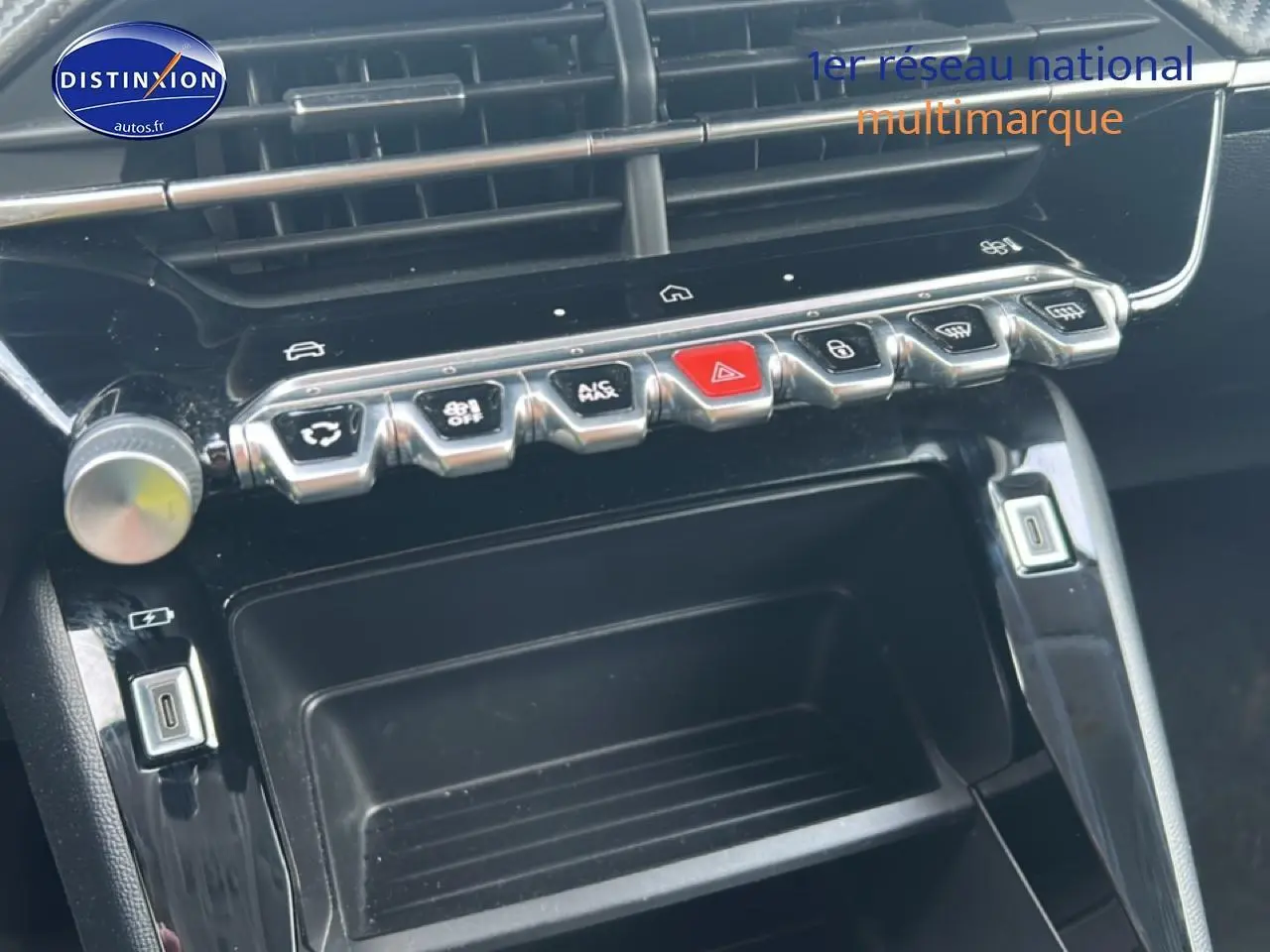 Gros plan sur la console centrale noire de la Peugeot 208 1.2 100 style, avec boutons de commande et ports USB visibles.