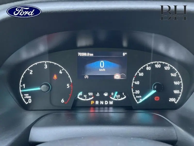 Tableau de bord numérique du Ford Transit Custom 2023, affichant vitesse, compte-tours et jauges, vue de face.