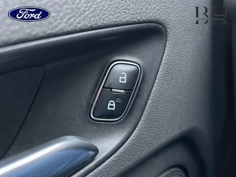 Gros plan sur les boutons de verrouillage centralisé noirs sur la porte intérieure du Ford Transit Custom bleu azur.