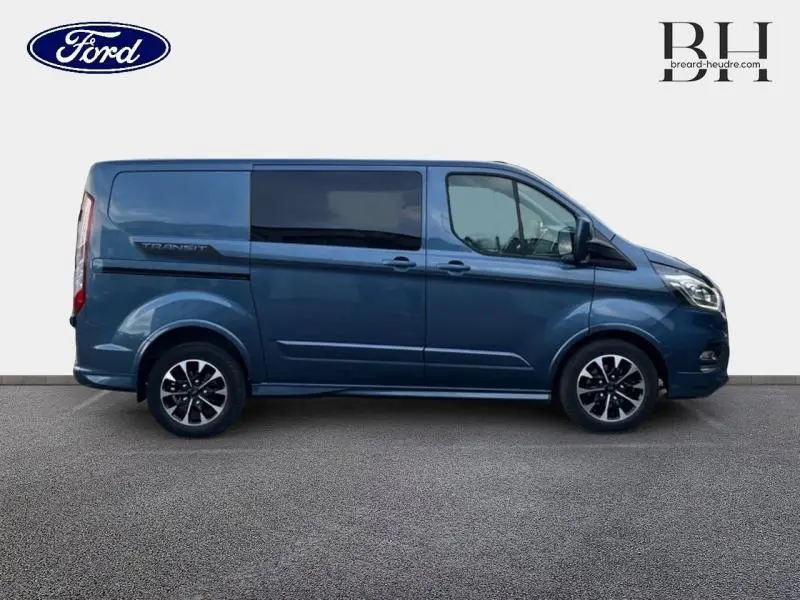 Vue de profil côté gauche du Ford Transit Custom Fourgon 2023 en bleu azur métallisé avec jantes alu noires et vitres arrière surteintées.