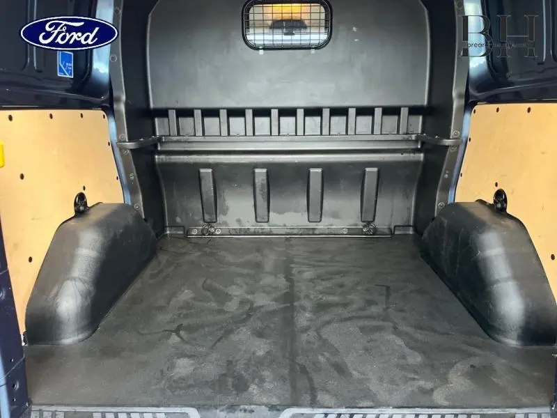 Vue intérieure arrière du fourgon Ford Transit Custom bleu azur, montrant l'espace de chargement vide avec cloison métallique.