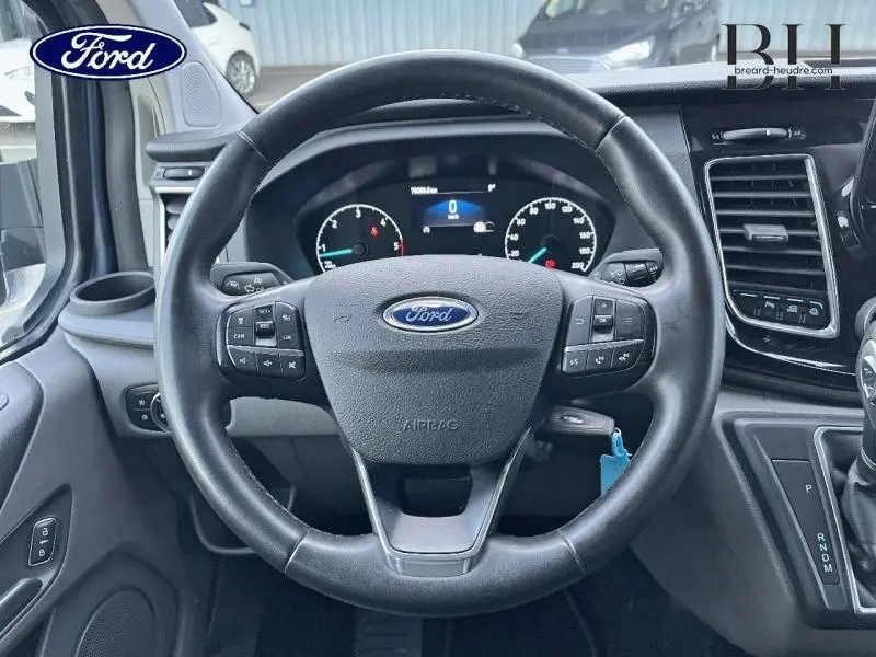Vue centrée sur le volant cuir noir du Ford Transit Custom 2023 avec tableau de bord et commandes intégrées.