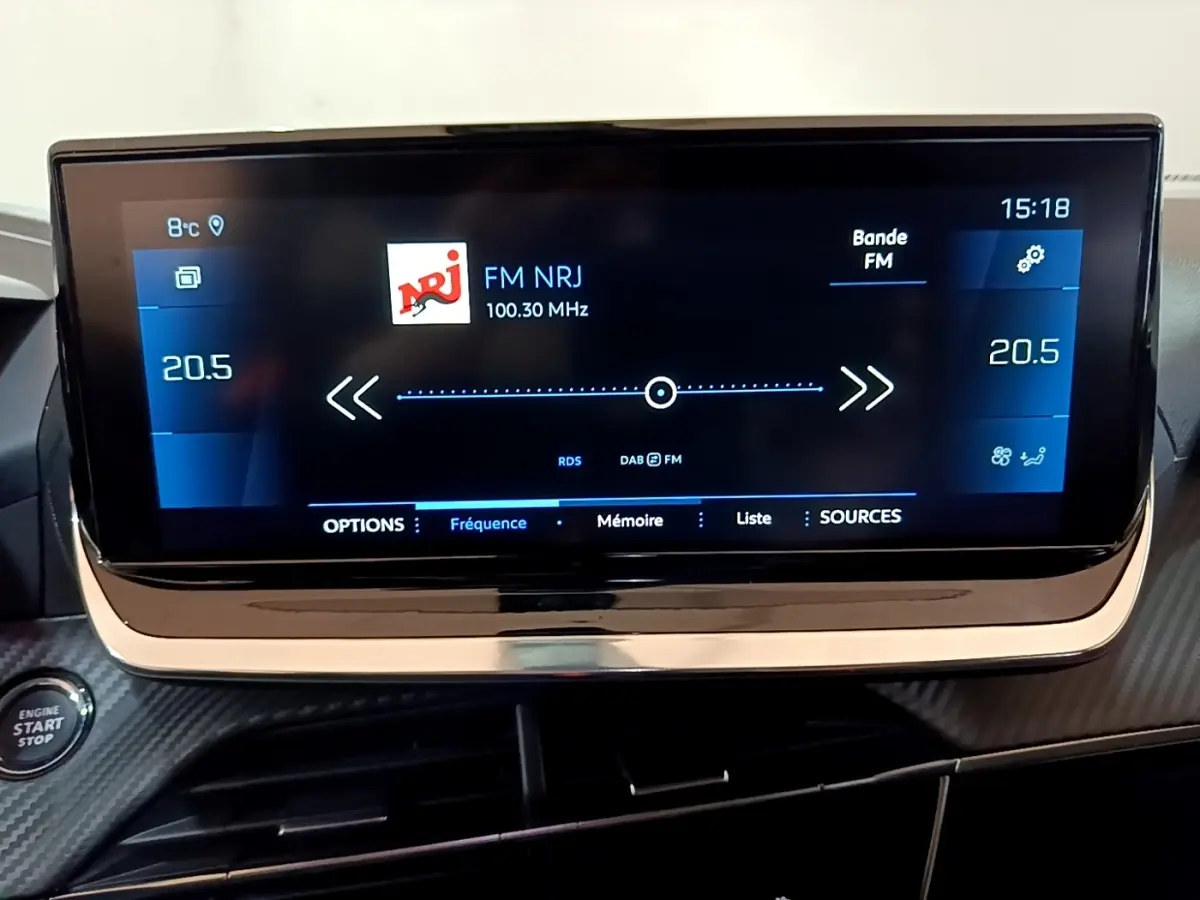 Écran tactile central de 10 pouces affichant la radio FM NRJ dans l’habitacle du Peugeot 2008 orange.