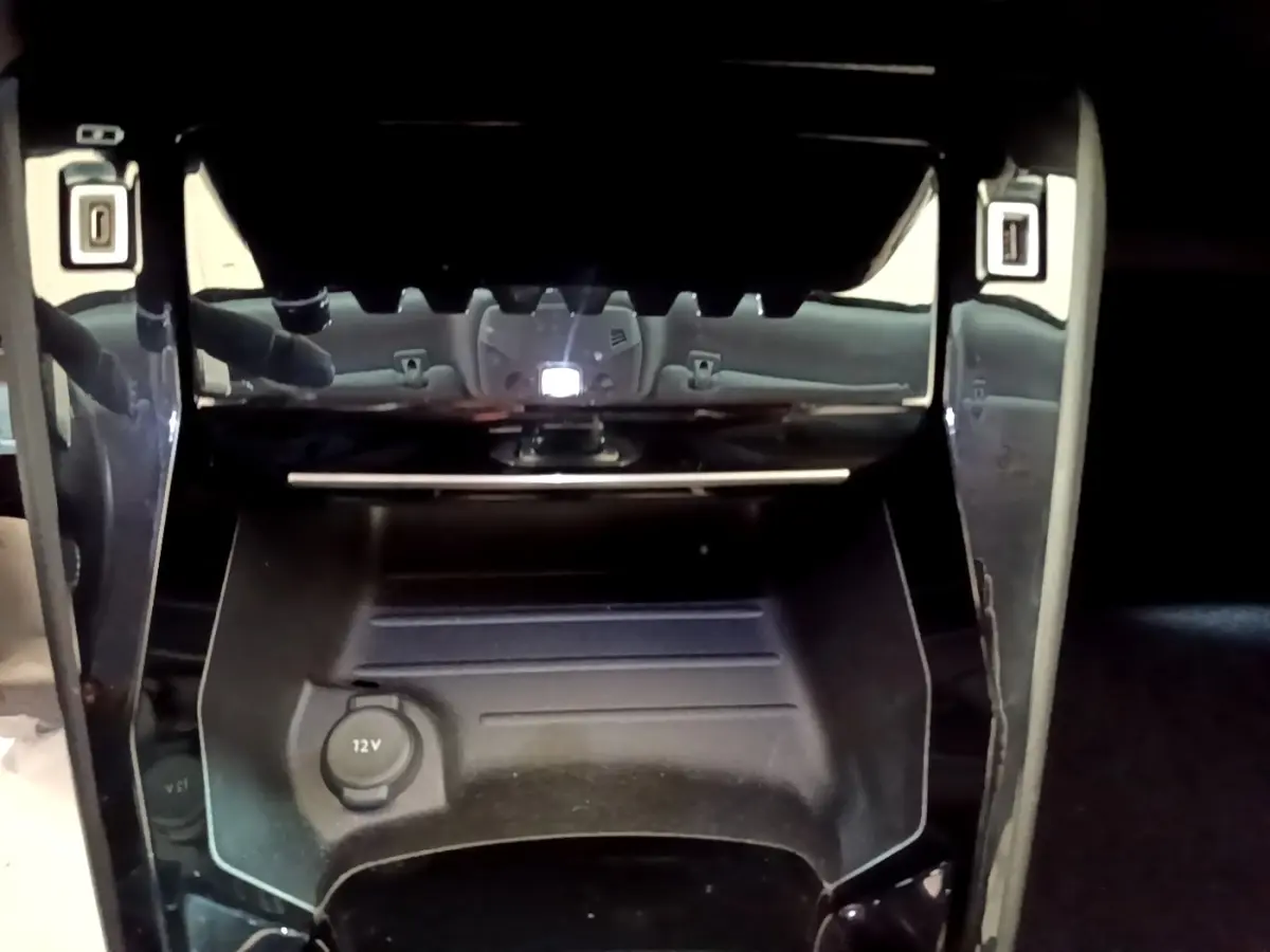 Prise 12V en gros plan dans la console centrale d’un Peugeot 2008 orange, version PureTech 130 Allure Business.