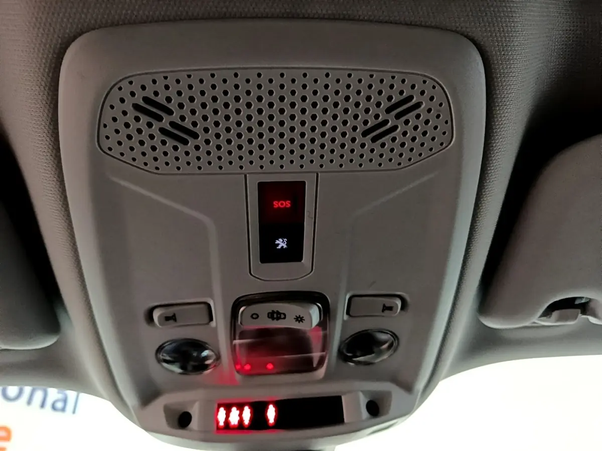 Vue en contre-plongée du panneau de commande intérieur au plafond avec bouton SOS rouge dans un Peugeot 2008 orange.