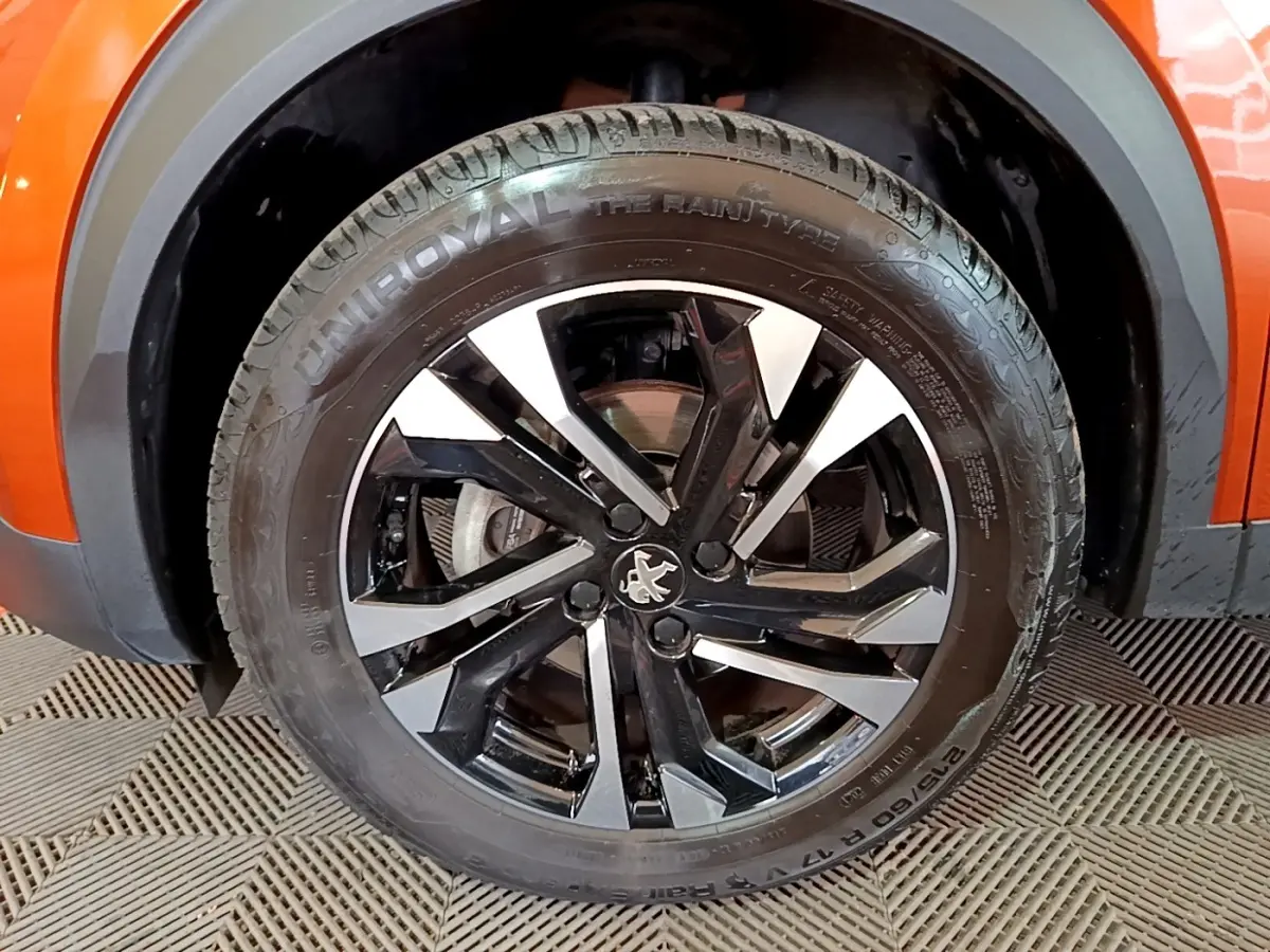 Gros plan sur la roue avant droite orange d’un Peugeot 2008 avec jante alliage noire et argentée au design moderne.
