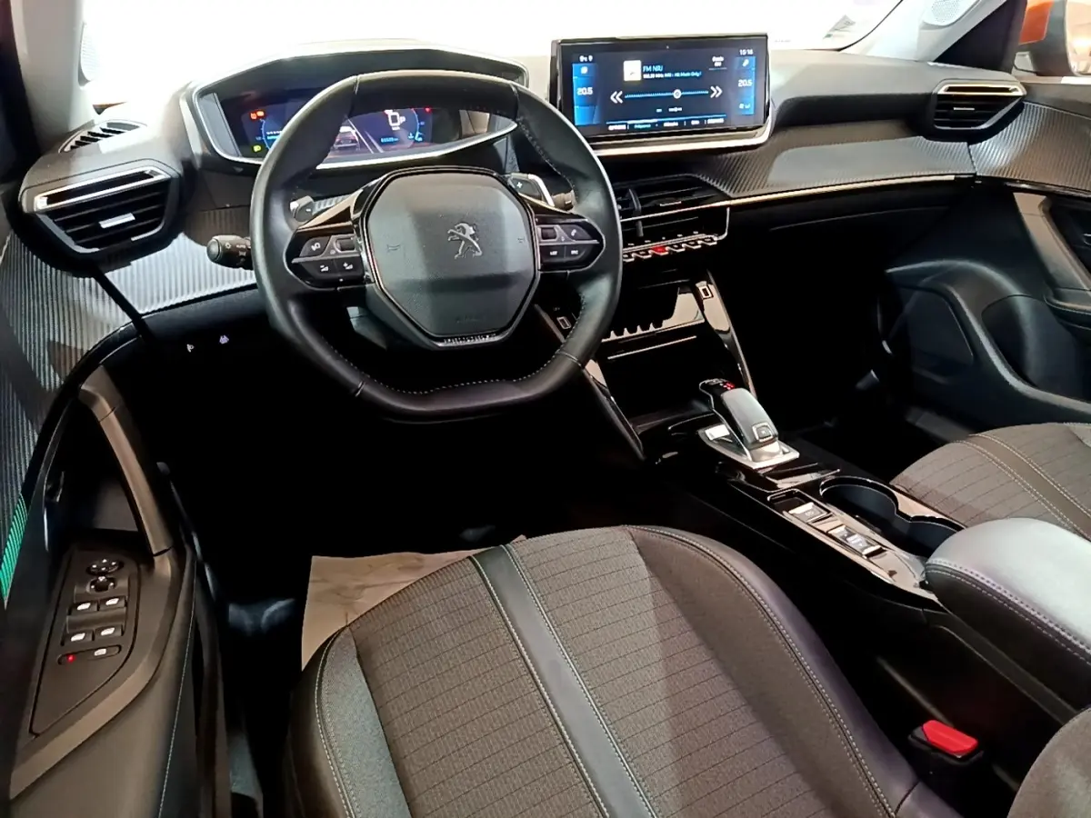 Vue intérieure avant du Peugeot 2008 avec volant cuir, écran tactile 10 pouces et sellerie tissu gris.