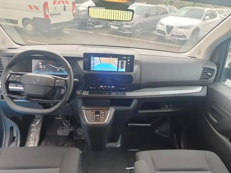 Vue intérieure avant du Citroën Jumpy gris, tableau de bord moderne avec écran tactile et volant multifonction cuir.