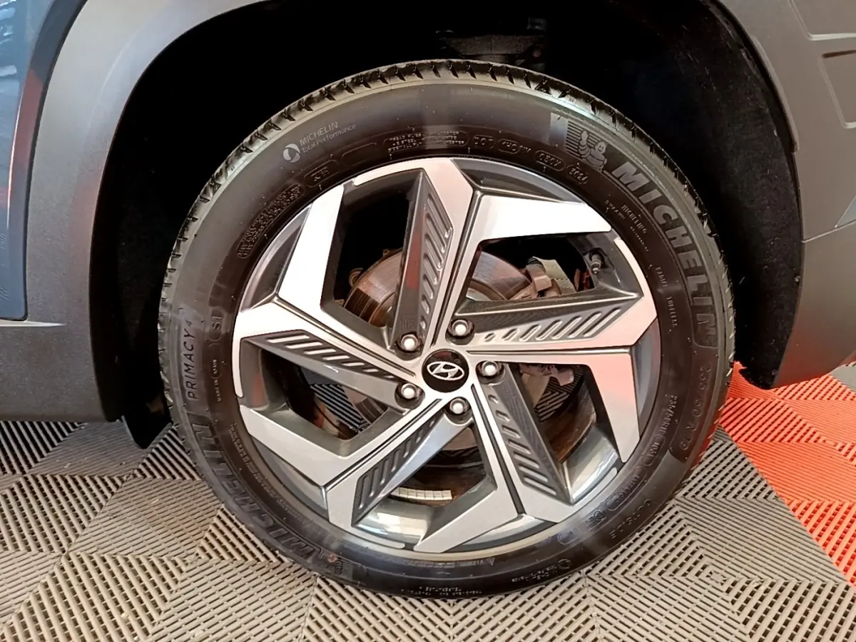 Gros plan sur la roue avant droite du Hyundai Tucson bleu, avec jante alliage au design géométrique moderne.