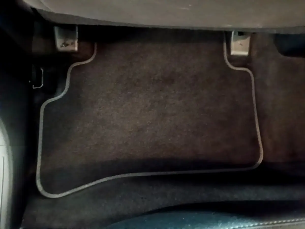 Vue rapprochée du tapis de sol noir côté conducteur du Hyundai Tucson bleu 2023 hybride rechargeable.