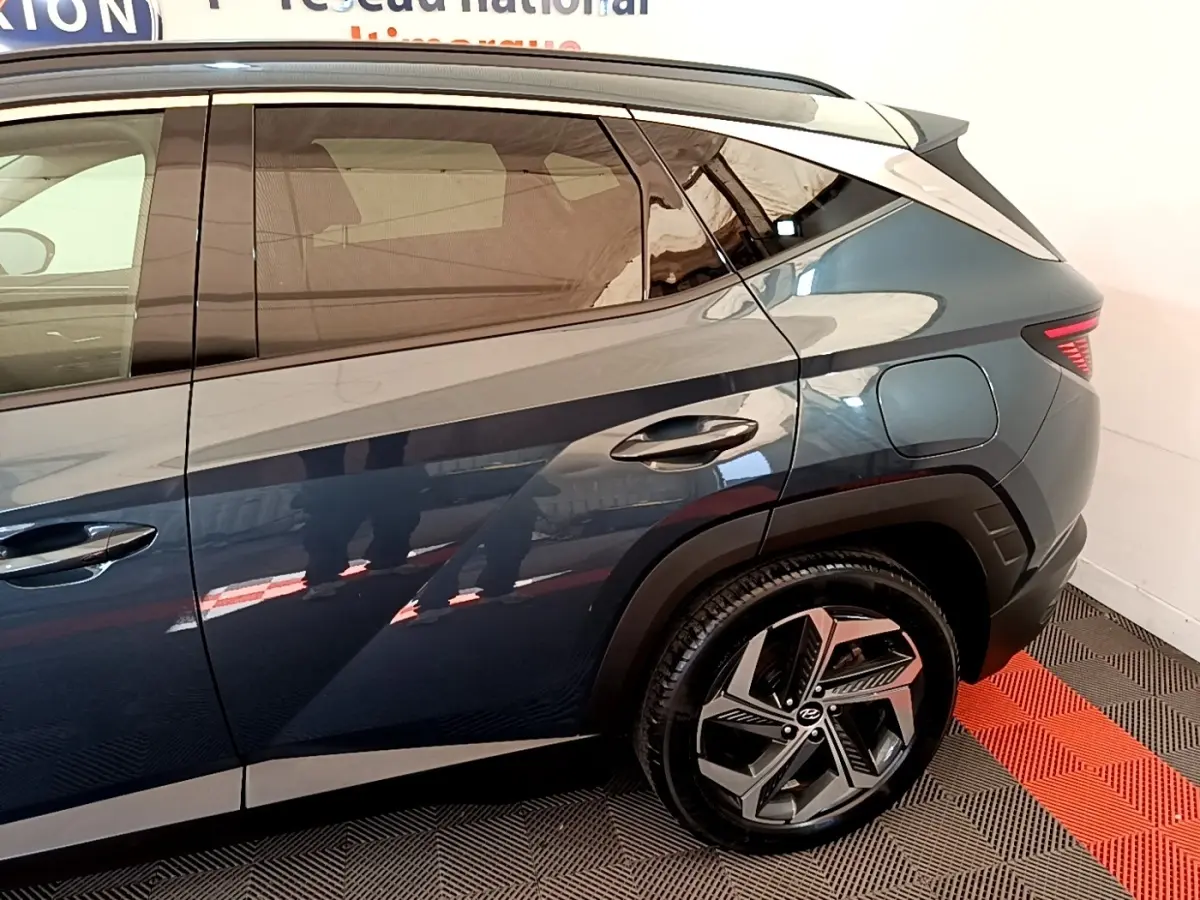 Vue côté droit arrière du Hyundai Tucson bleu 2023 avec jante alliage et feux arrière LED distinctifs.