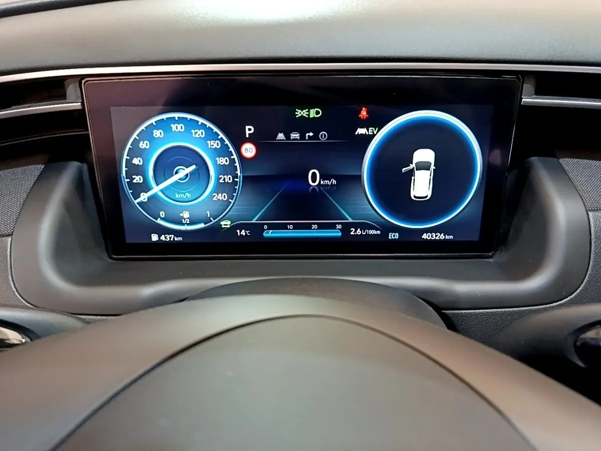 Tableau de bord numérique du Hyundai Tucson 2023, affichage couleur avec vitesse et indicateurs, vue de face depuis le volant.