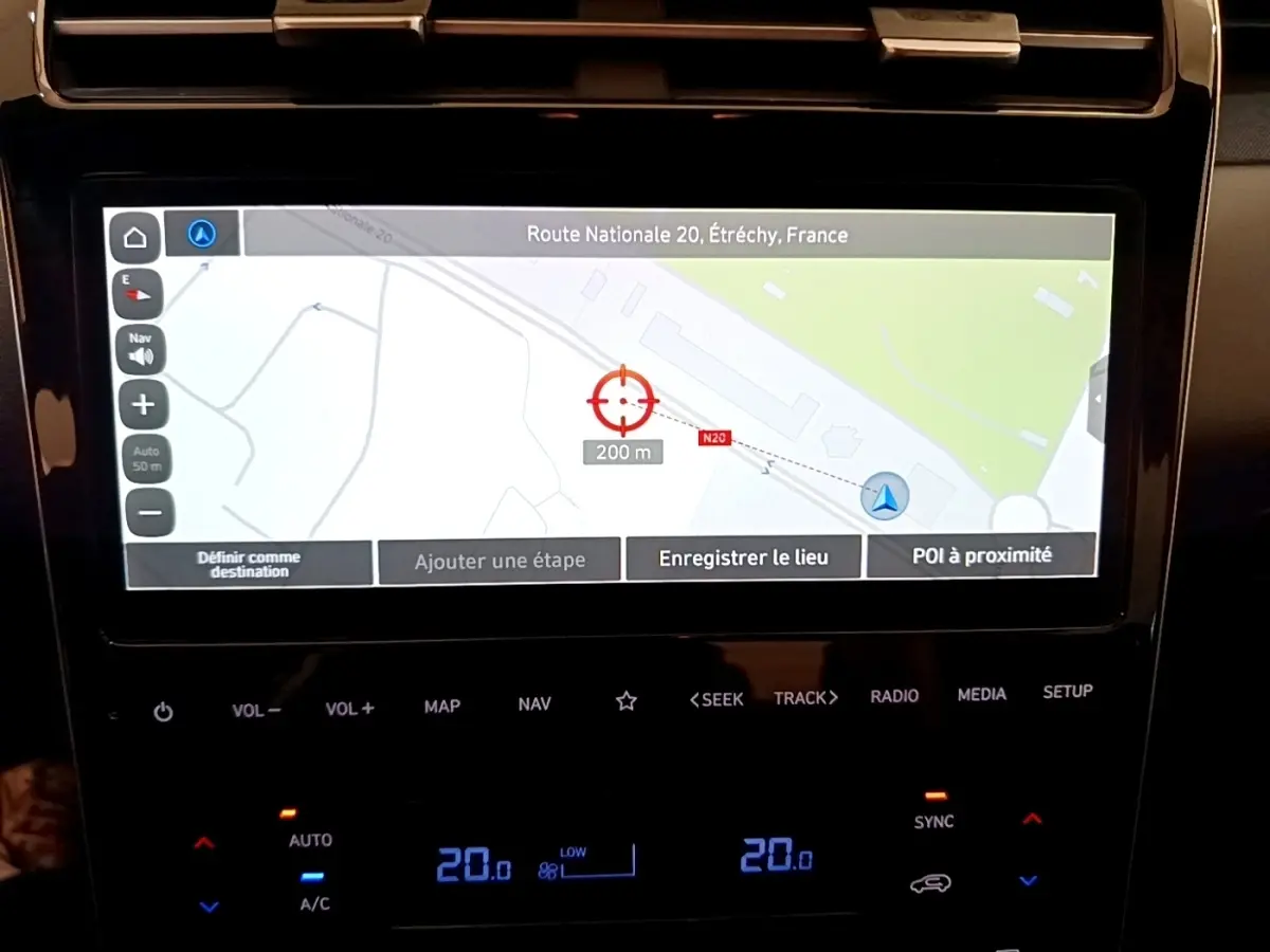 Écran tactile central du Hyundai Tucson bleu 2023 montrant la navigation GPS et commandes climatisation digitales.