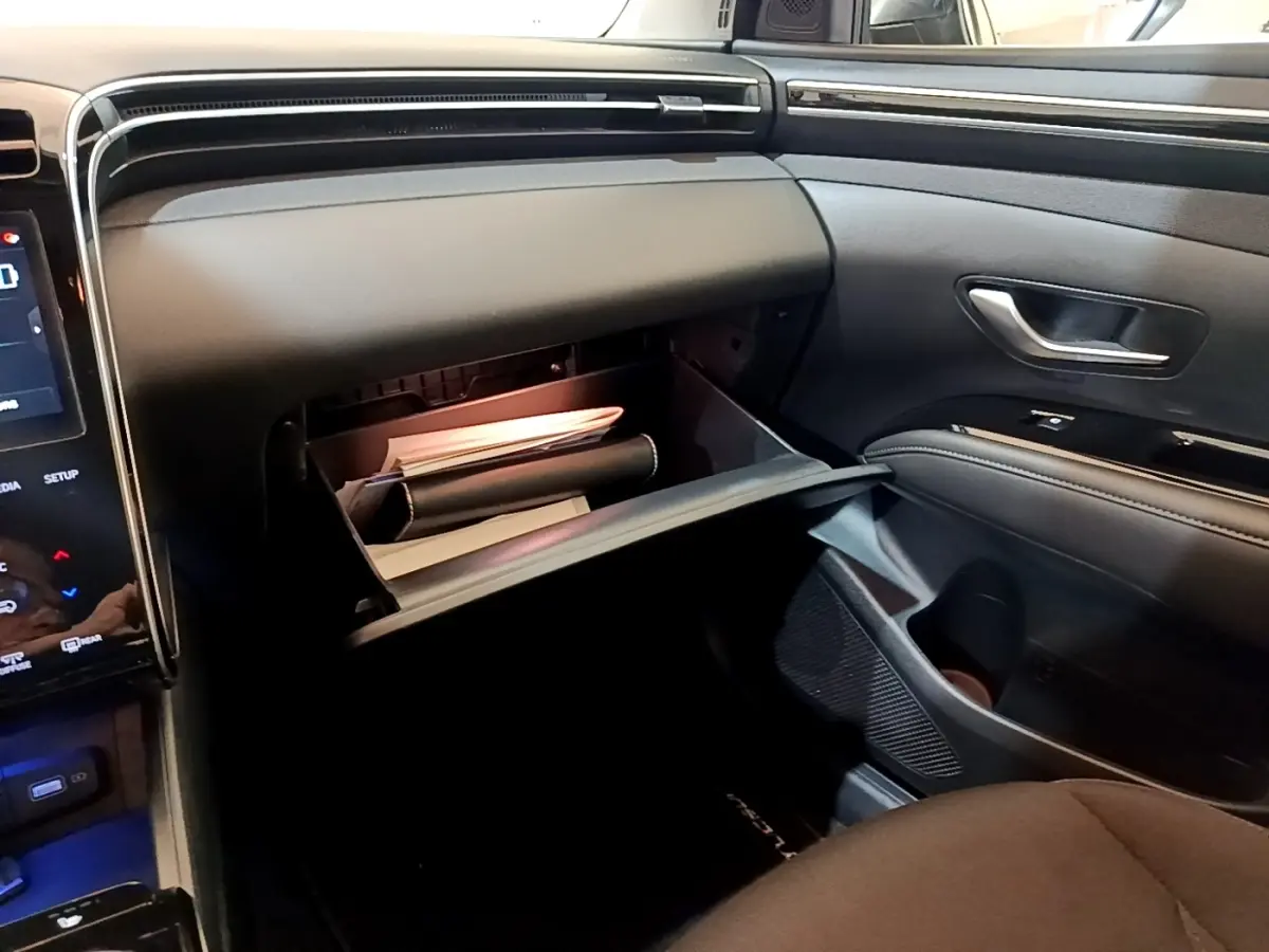 Vue intérieure côté passager du Hyundai Tucson 2023, boîte à gants ouverte avec documents visibles.