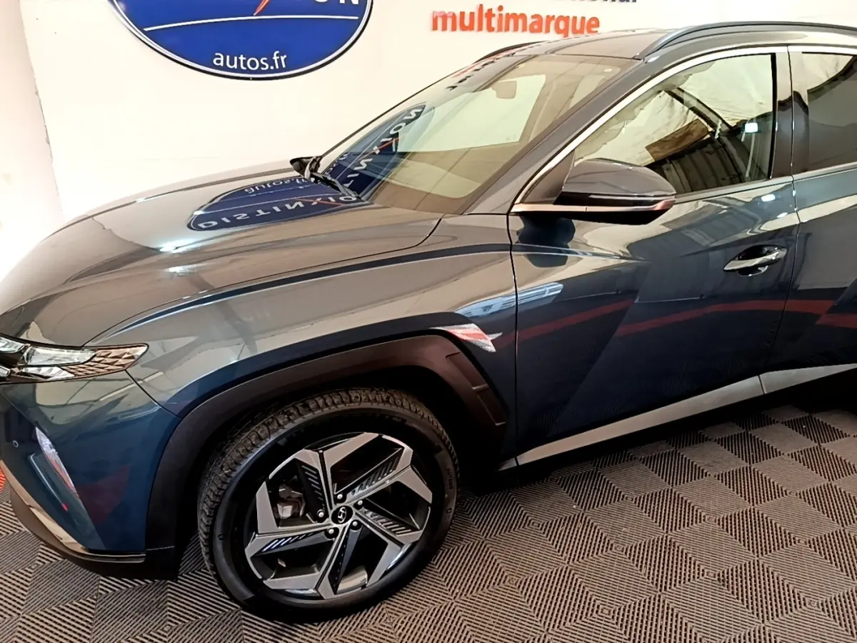 Vue de profil côté gauche d'un Hyundai Tucson bleu 2023 avec jantes alliage et rétroviseur noir brillant.