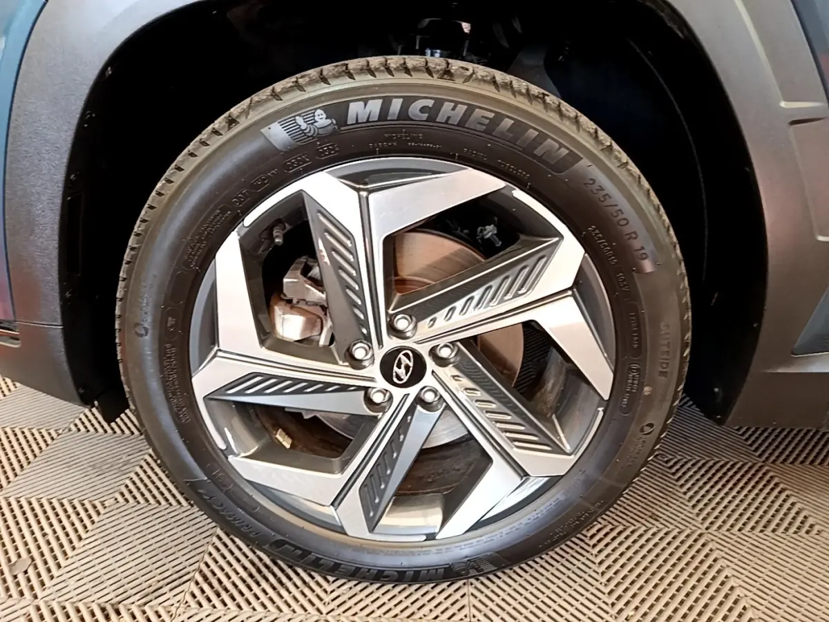 Gros plan sur la roue avant droite du Hyundai Tucson bleu 2023 avec jante alliage et pneu Michelin.