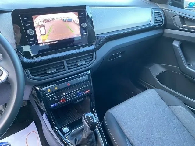 Vue intérieure côté passager du tableau de bord noir et gris du Volkswagen T-Cross 2025 avec écran tactile affichant la caméra de recul.