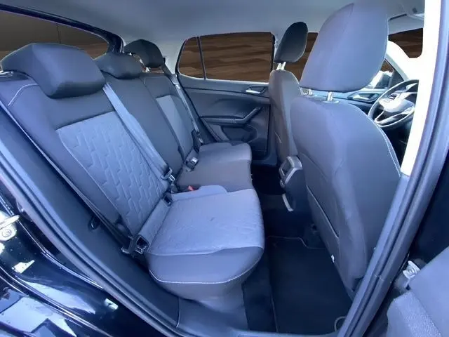 Vue intérieure arrière du Volkswagen T-Cross noir 2025, montrant la banquette 3 places avec sièges en tissu gris et ceintures de sécurité.