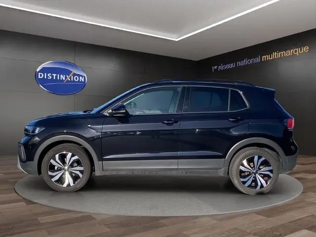 Vue de profil côté gauche d'un Volkswagen T-Cross noir 2025 sur fond intérieur avec jantes alliage bicolores.