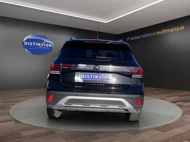 Vue arrière d’un Volkswagen T-Cross noir 2025 avec feux LED et logo distinctif sur fond showroom.