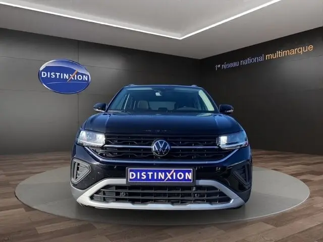 Vue avant d’un Volkswagen T-Cross noir 2025 avec calandre noire et détails argentés, en showroom Distinxion.