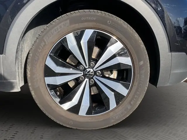 Gros plan sur la roue avant droite noire d’un Volkswagen T-Cross 2025 avec jante alliage bicolore brillante.
