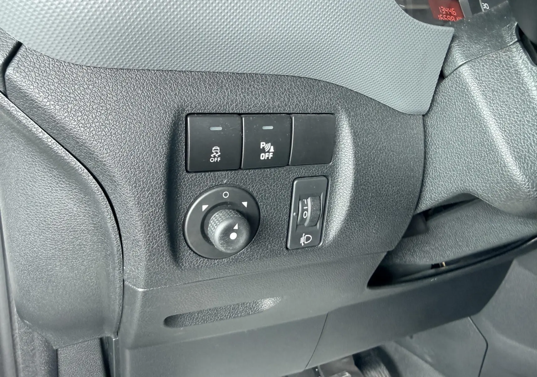 Détail des commandes de réglage des rétroviseurs et des feux sur le côté gauche du tableau de bord d’un Citroën Berlingo blanc.