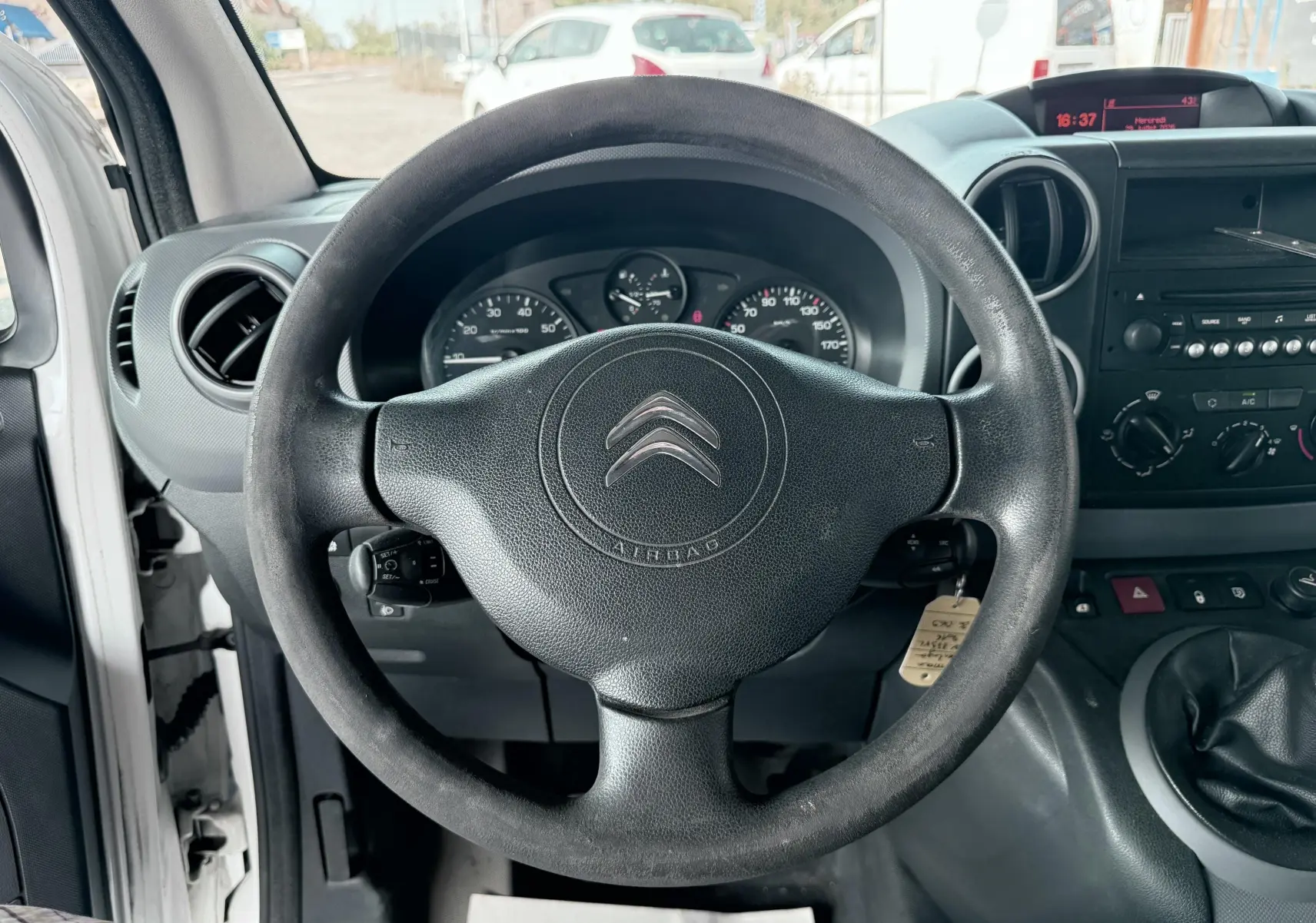 Vue intérieure centrée sur le volant noir du Citroën Berlingo blanc, avec tableau de bord et commandes visibles.