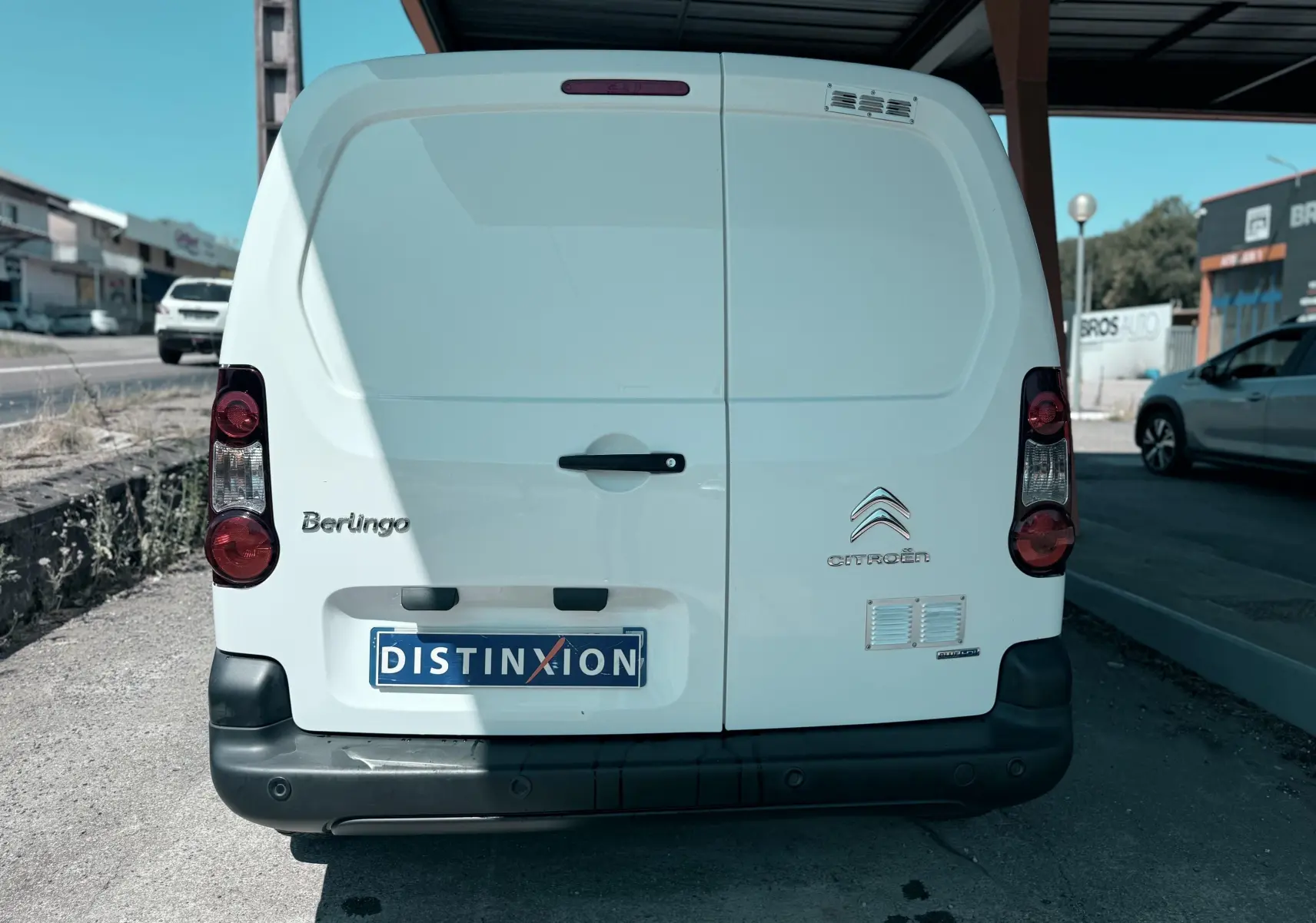 Vue arrière d’un utilitaire Citroën Berlingo blanc, avec portes battantes et feux arrière verticaux.