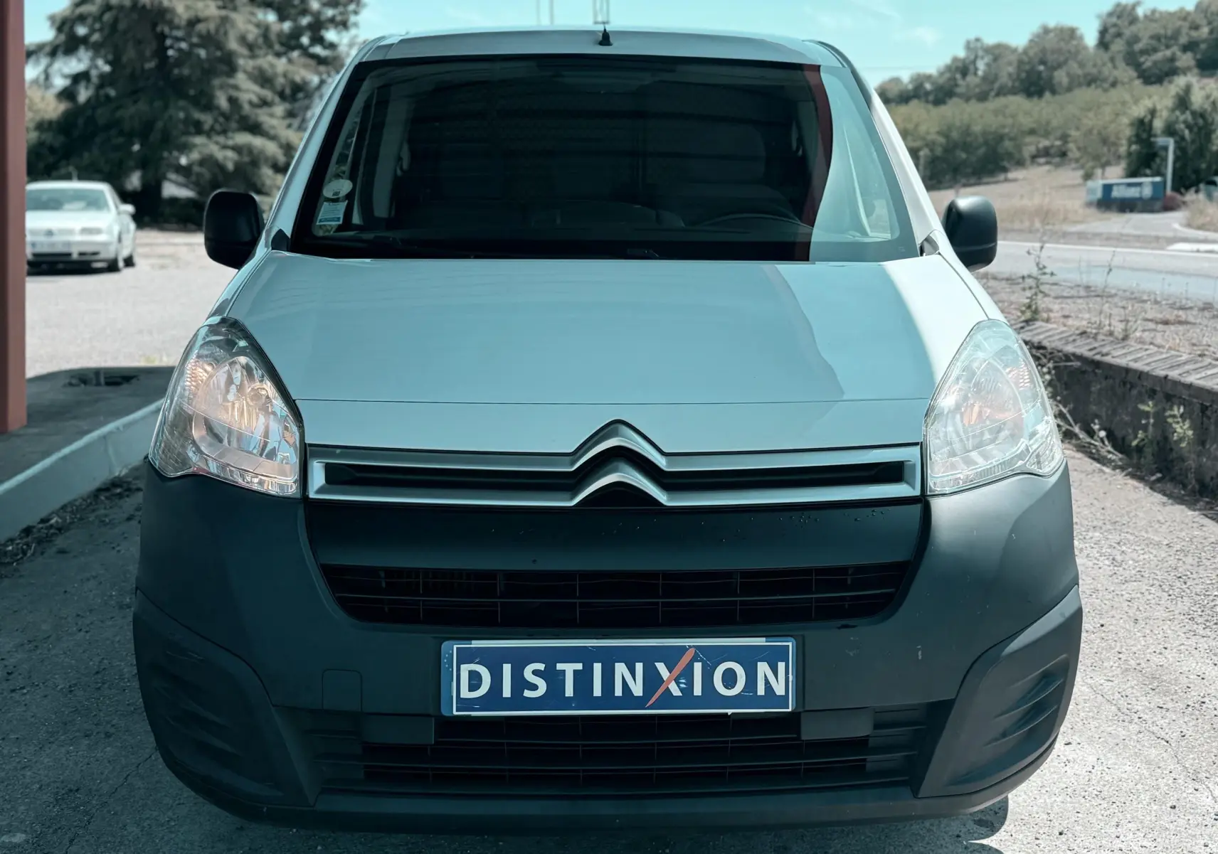 Vue frontale d’un Citroën Berlingo blanc de 2016 avec pare-chocs noir et plaque Distinxion visible.