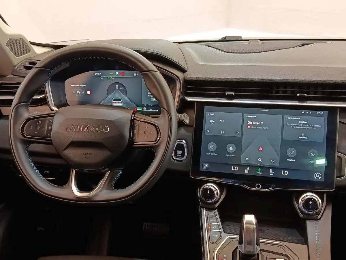 Vue intérieure centrée sur le volant cuir noir et l’écran tactile central du tableau de bord du Lynk & Co 01 hybride.