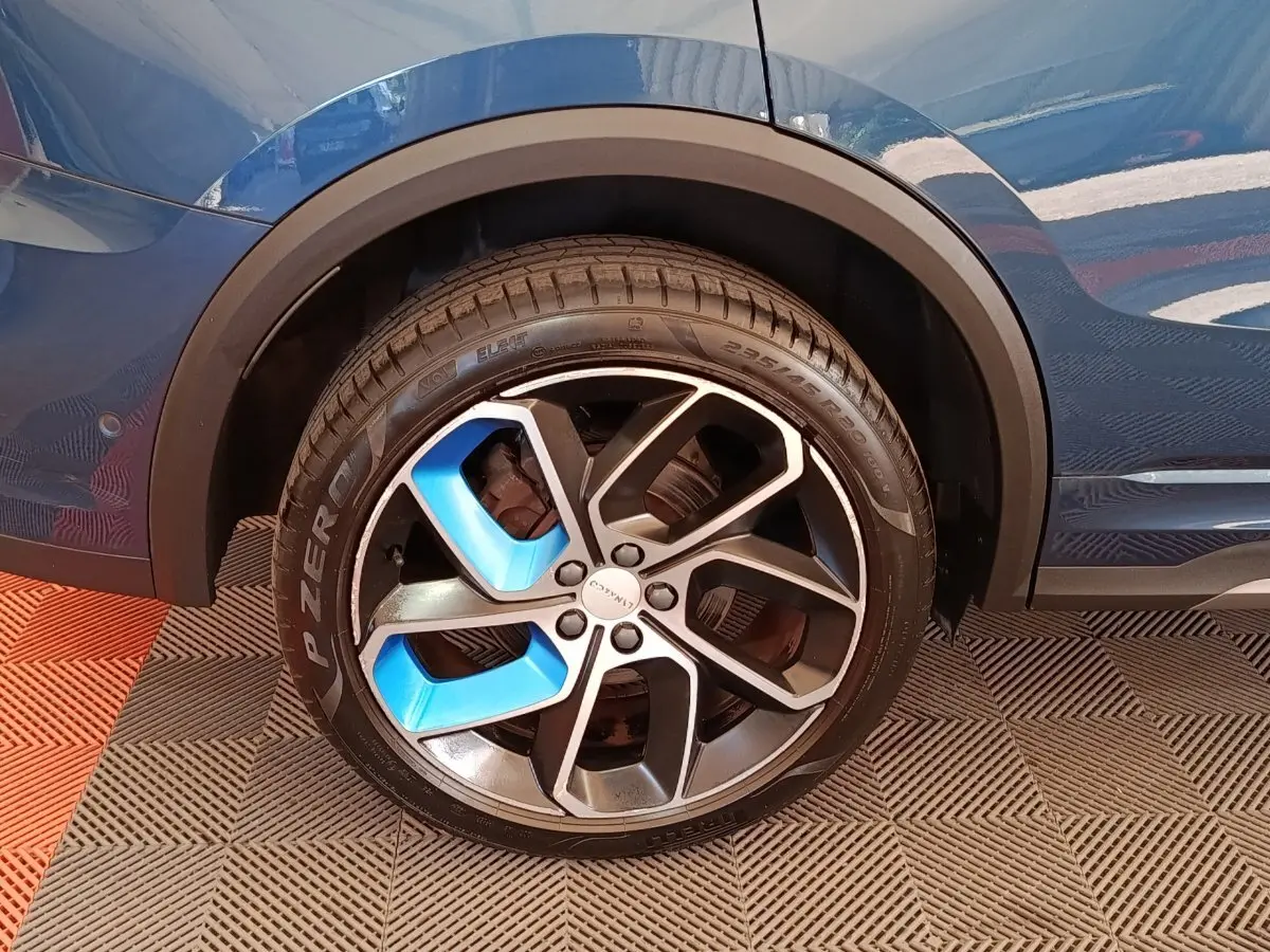 Gros plan sur la roue avant droite bleu et noire du SUV hybride rechargeable Link & Co 01 bleu 2023.