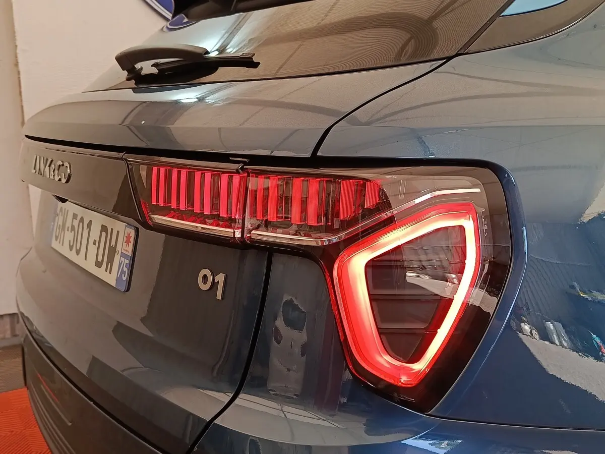 Vue arrière droite du SUV bleu LINK & CO 01 avec feux arrière LED allumés et logo visible sur le hayon.