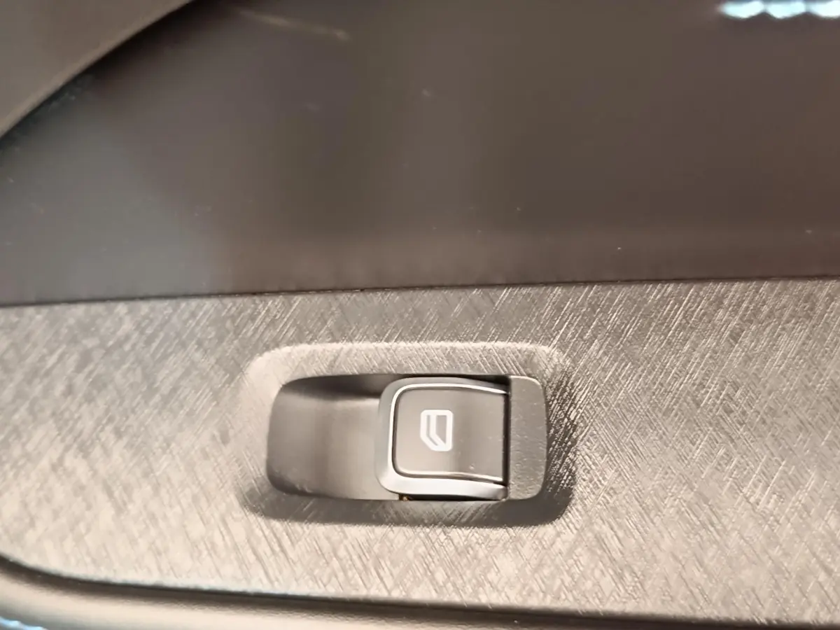 Gros plan sur bouton de lève-vitre intégré dans panneau intérieur gris texturé d’un Link & Co 01 bleu.