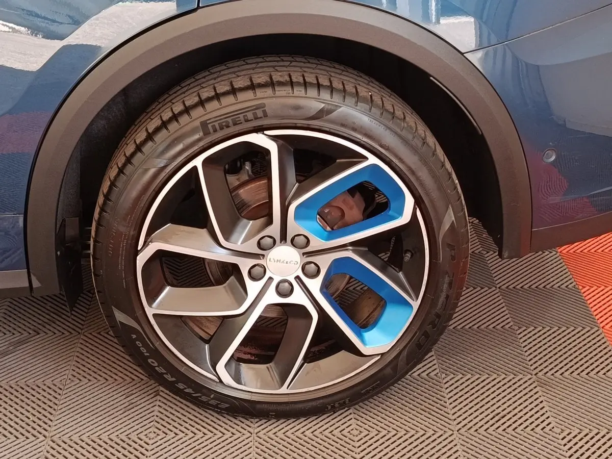 Gros plan sur la roue arrière droite bleu métallisé du Lynk & Co 01 avec jante alliage noire et bleue.