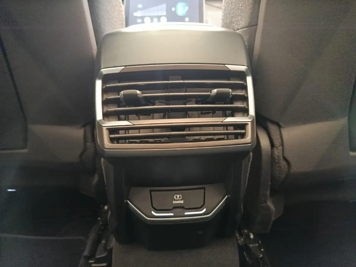 Vue rapprochée de la console arrière avec prise de charge sans fil et aérateurs du LINK & CO 01 bleu 2023.