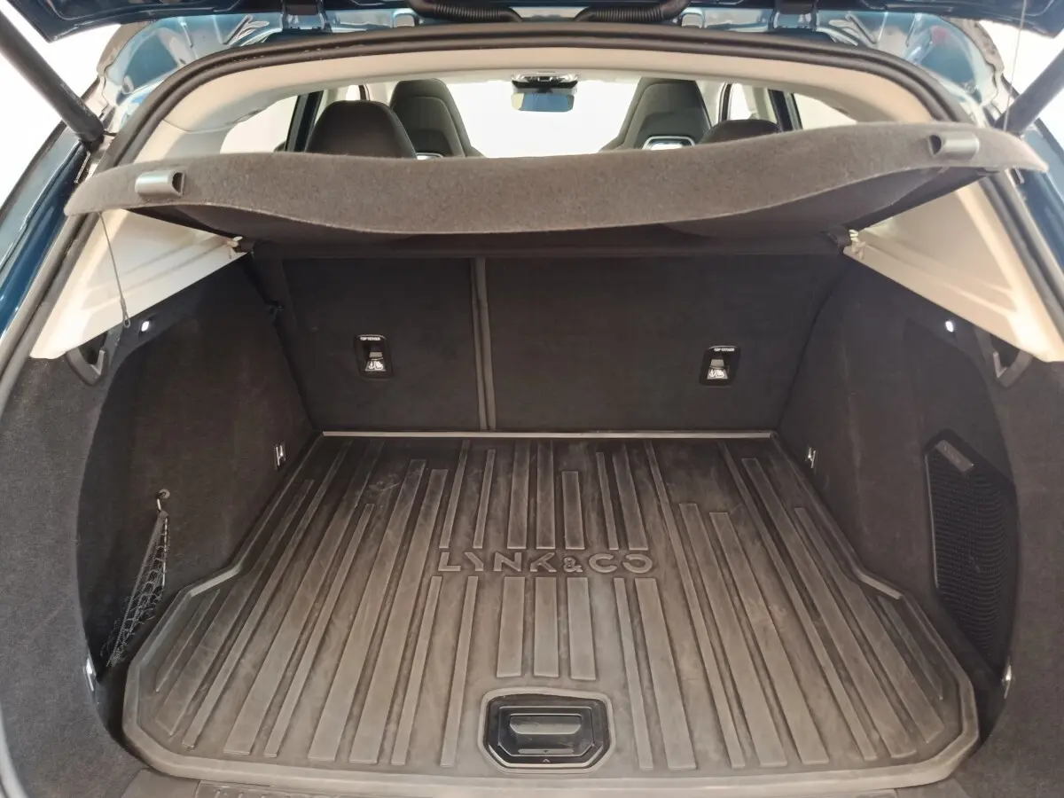 Vue intérieure du coffre ouvert du Lynk & Co 01 bleu, avec tapis de protection marqué Lynk & Co.