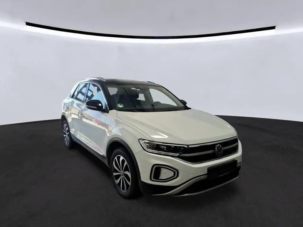 Volkswagen T-Roc blanc pur avec toit noir, vue 3/4 avant droit, jantes alliage et calandre chromée.