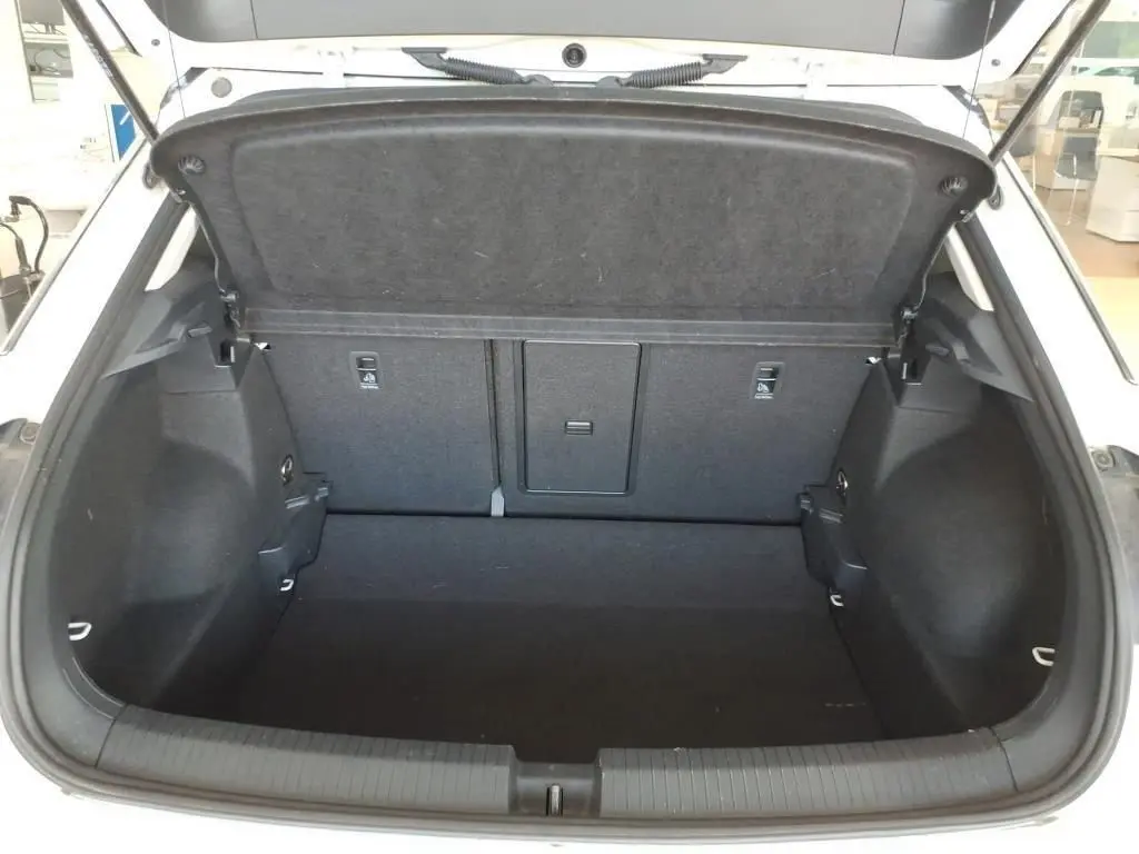 Vue intérieure du coffre ouvert du Volkswagen T-Roc blanc pur avec toit noir, montrant un espace de chargement propre et spacieux.