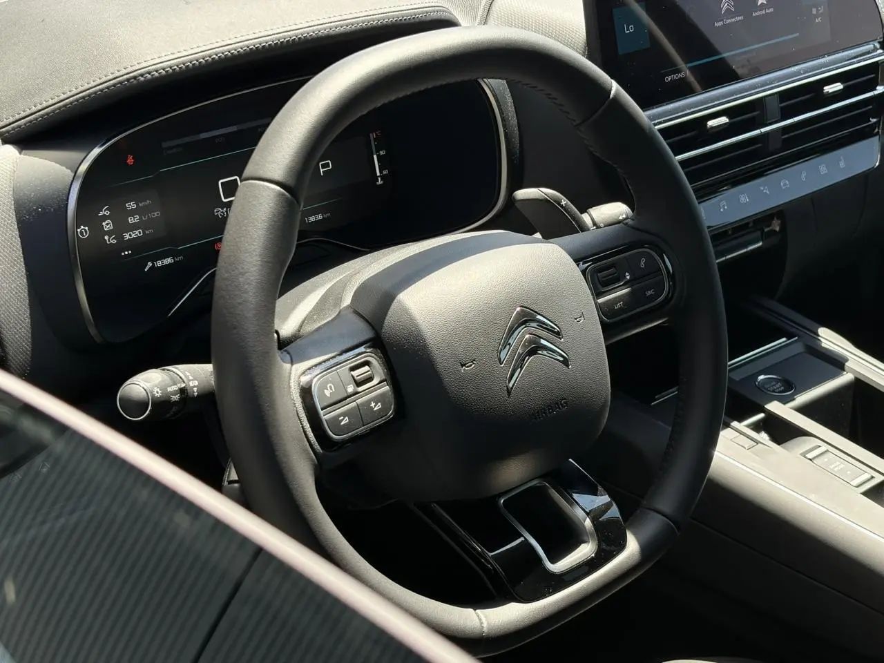 Vue rapprochée du volant cuir noir et du combiné numérique de la Citroën C5 Aircross Hybrid 2025, intérieur moderne et épuré.