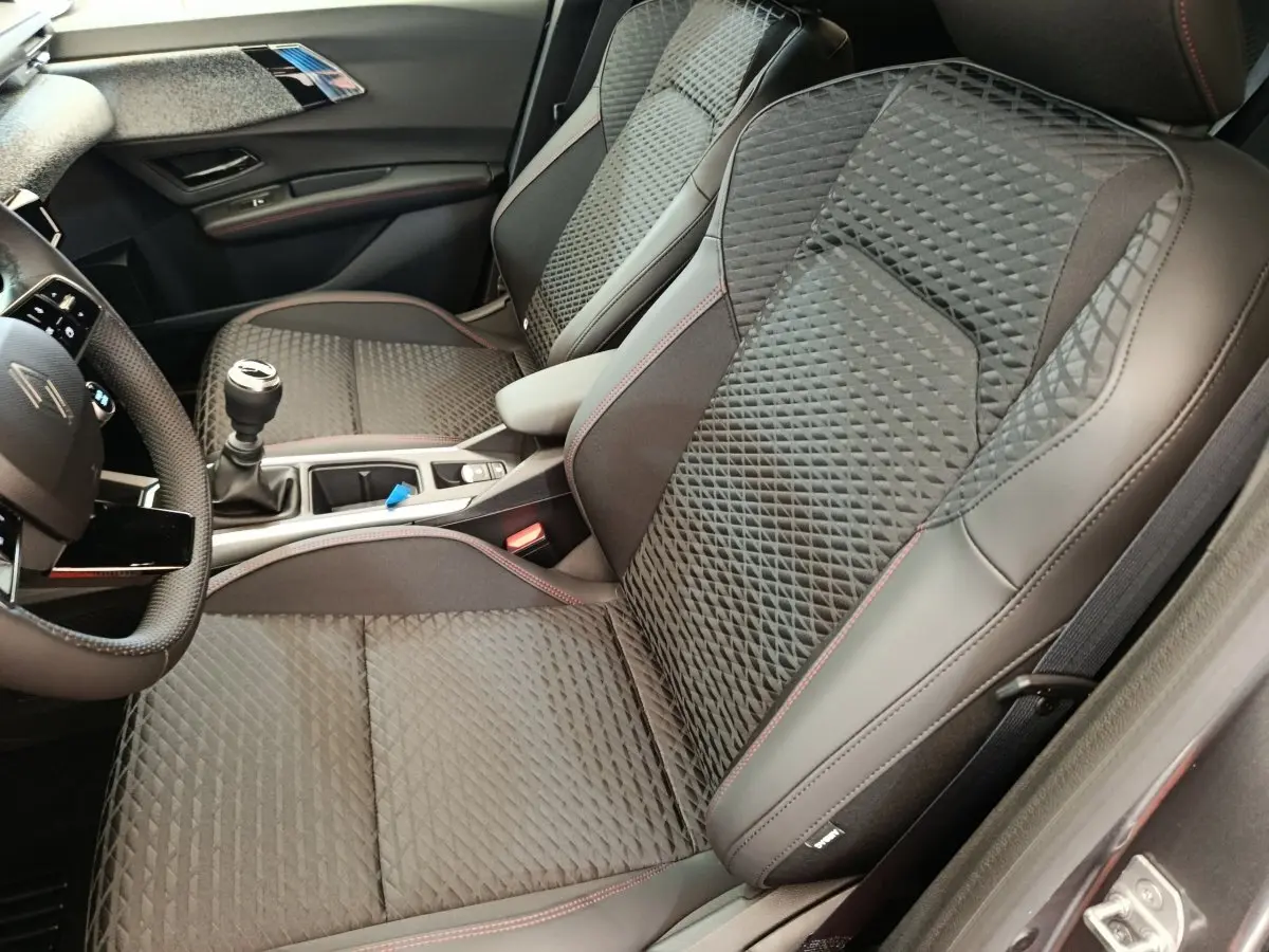 Vue intérieure côté droit des sièges avant gris foncé avec surpiqûres rouges et console centrale d'une Renault Clio Techno TCe 115 2026.