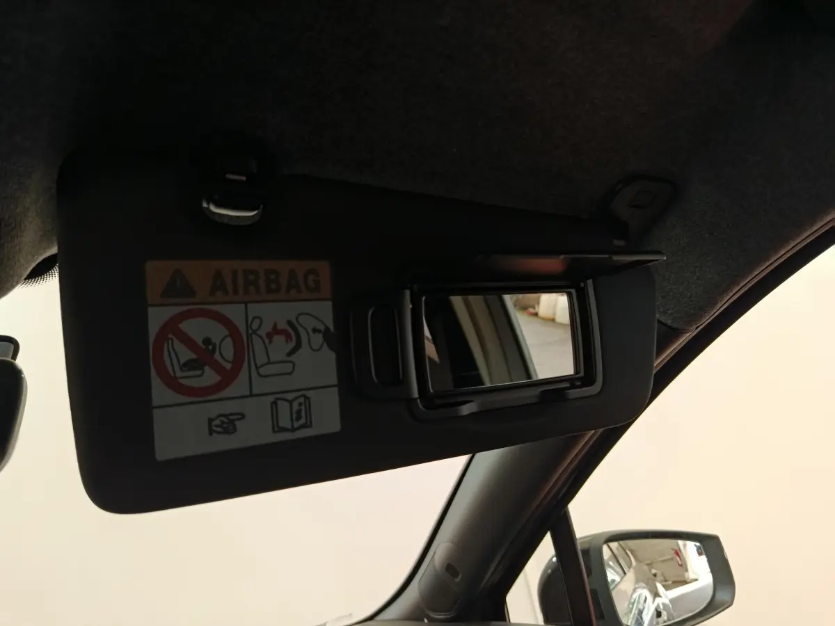 Détail du pare-soleil côté conducteur avec miroir de courtoisie ouvert et avertissement airbag visible dans une Renault Clio 2026.