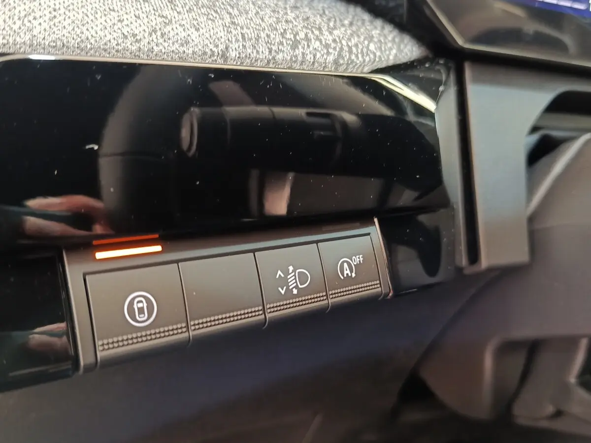 Détail intérieur montrant les boutons de réglage des phares et désactivation du start/stop sur tableau de bord noir.